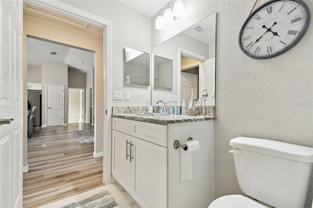 bathroom with hardwood / wood-style flooring, lofted ceiling, vanity, and toilet