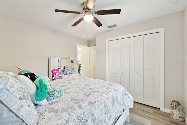 bedroom with ceiling fan, light hardwood / wood-style floors, and a closet