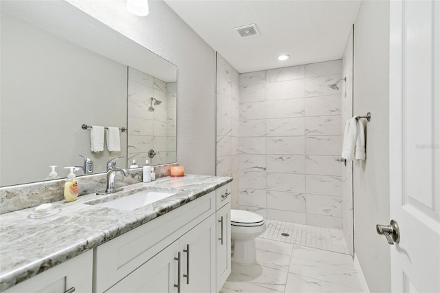 bathroom featuring tiled shower, vanity, and toilet