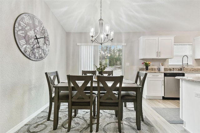 dining area featuring an inviting chandelier, sink, light hardwood / wood-style flooring, and a healthy amount of sunlight