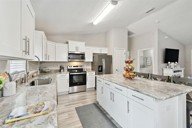 kitchen with a breakfast bar area, stainless steel appliances, independent washer and dryer, a center island, and white cabinets