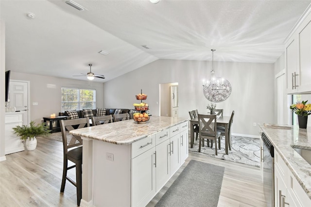 kitchen featuring a kitchen island, stainless steel dishwasher, white cabinets, and a kitchen breakfast bar