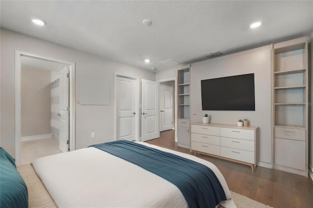 bedroom with dark hardwood / wood-style flooring and ensuite bath