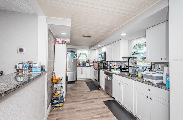 kitchen with dark stone countertops, sink, white cabinets, and appliances with stainless steel finishes