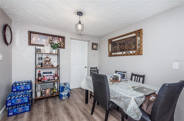 dining room with wood-type flooring and a textured ceiling