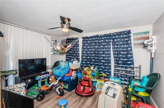 rec room featuring ceiling fan, wood-type flooring, and a textured ceiling