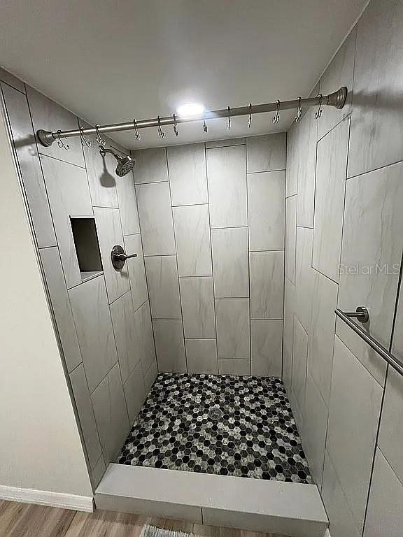 bathroom with wood-type flooring and tiled shower