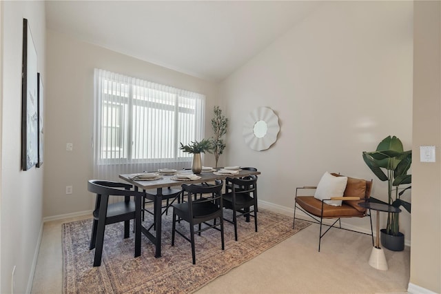 carpeted dining room featuring lofted ceiling