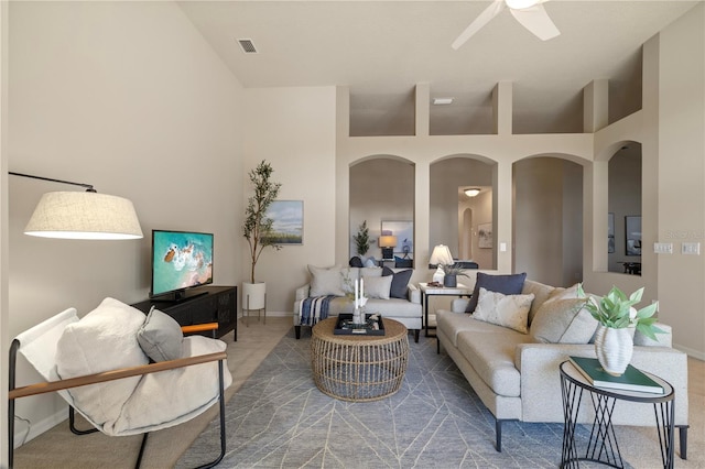 living room with carpet floors, ceiling fan, and a high ceiling