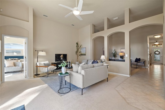 living room with ceiling fan, high vaulted ceiling, and light carpet