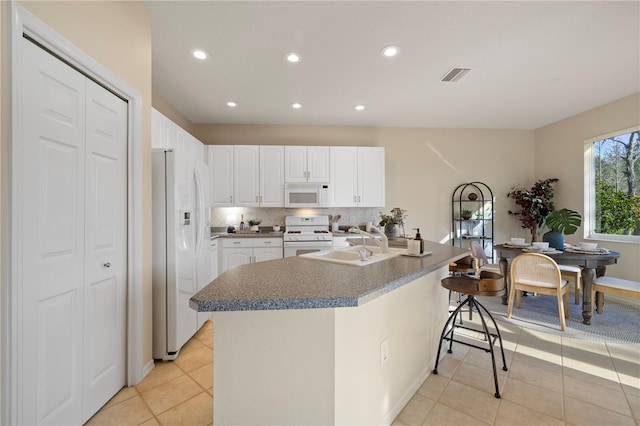 kitchen with sink, white cabinetry, light tile patterned floors, white appliances, and backsplash