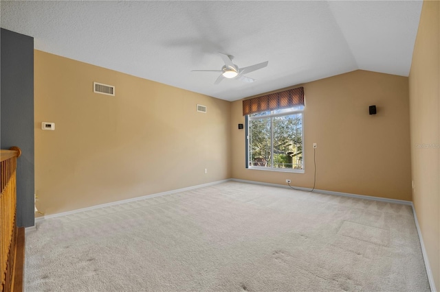 carpeted empty room with vaulted ceiling, a textured ceiling, and ceiling fan