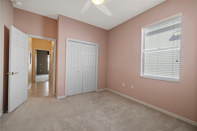 unfurnished bedroom featuring ceiling fan, a closet, and light carpet