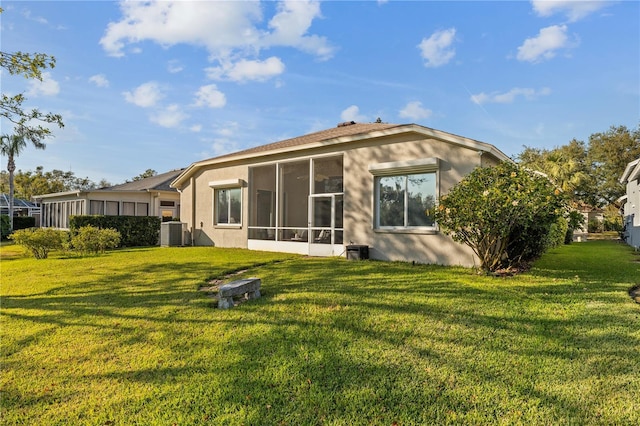 rear view of house with central AC, a sunroom, and a lawn