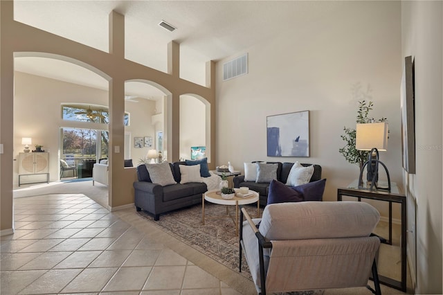 living room featuring a towering ceiling, ceiling fan, and light tile patterned flooring