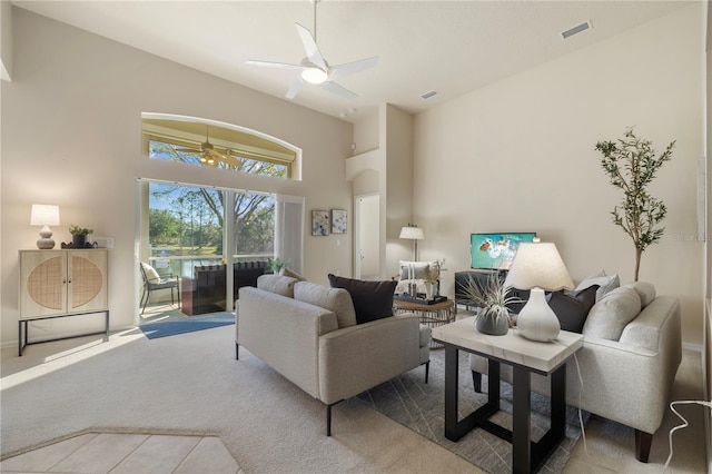 carpeted living room with ceiling fan and a high ceiling