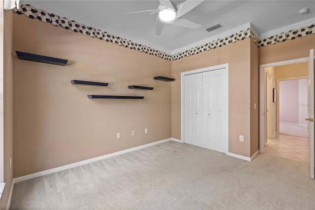 unfurnished bedroom with light colored carpet, ceiling fan, and a closet