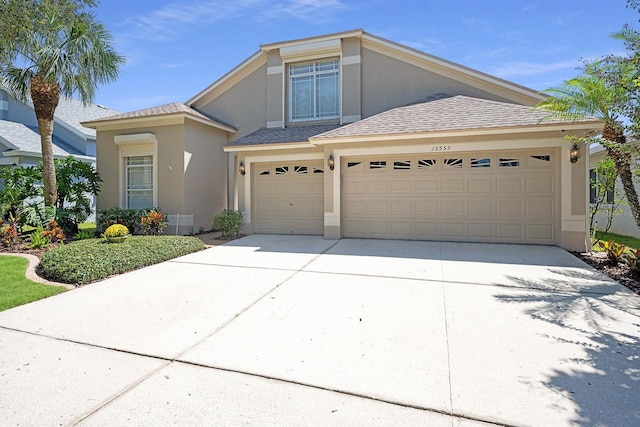 view of front facade with a shingled roof, driveway, and stucco siding