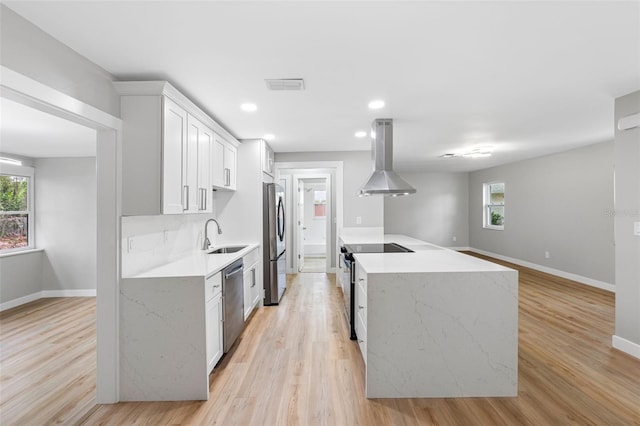 kitchen featuring sink, white cabinetry, a healthy amount of sunlight, island exhaust hood, and stainless steel appliances