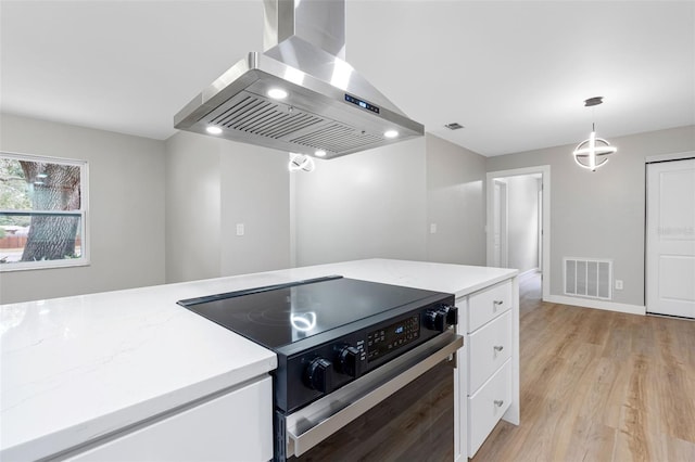 kitchen with electric range oven, decorative light fixtures, white cabinetry, island exhaust hood, and light wood-type flooring