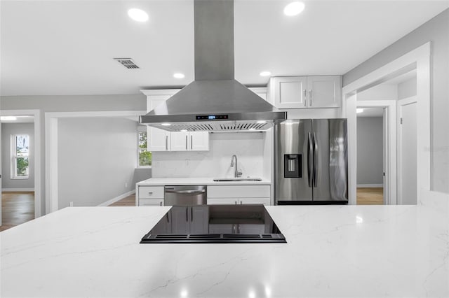 kitchen featuring sink, stainless steel appliances, light stone countertops, white cabinets, and island exhaust hood