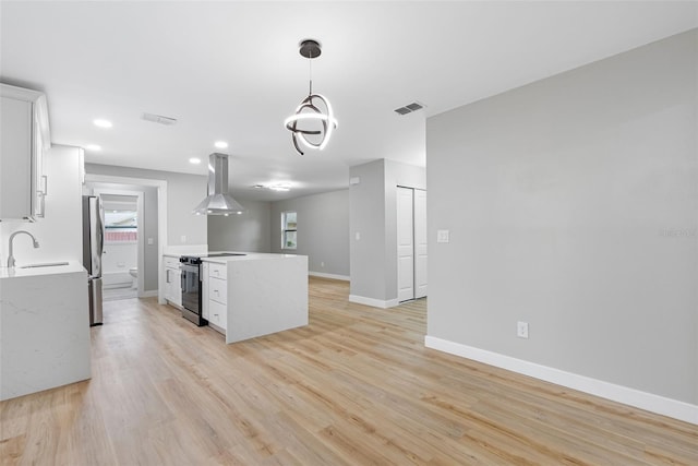 kitchen featuring pendant lighting, island range hood, white cabinetry, stainless steel appliances, and light hardwood / wood-style flooring