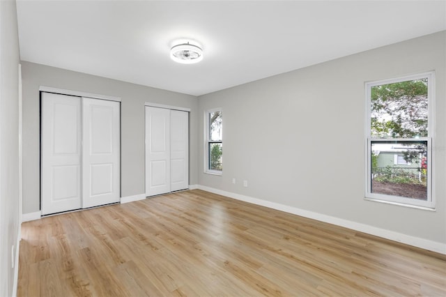 unfurnished bedroom featuring light hardwood / wood-style floors and multiple closets