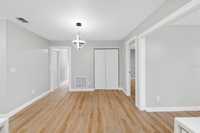 unfurnished dining area featuring a notable chandelier and light wood-type flooring