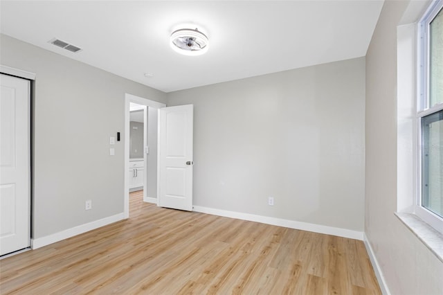 unfurnished bedroom with multiple windows, light hardwood / wood-style floors, and a closet