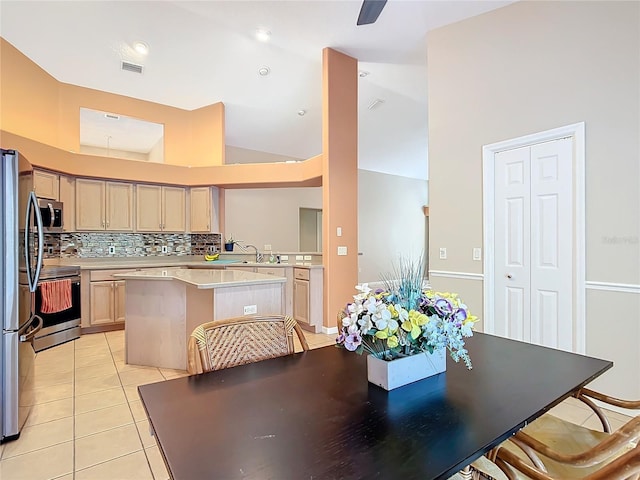 kitchen with light brown cabinetry, tasteful backsplash, light tile patterned floors, a kitchen island, and stainless steel appliances