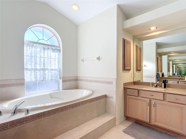 bathroom featuring vanity, tiled tub, vaulted ceiling, and tile patterned floors