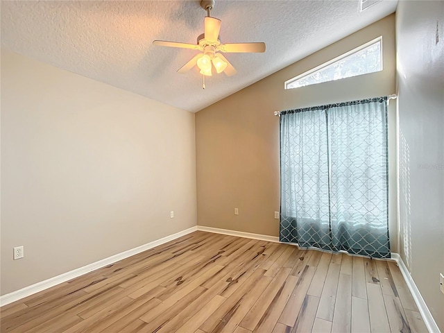 spare room featuring hardwood / wood-style flooring, ceiling fan, vaulted ceiling, and a textured ceiling