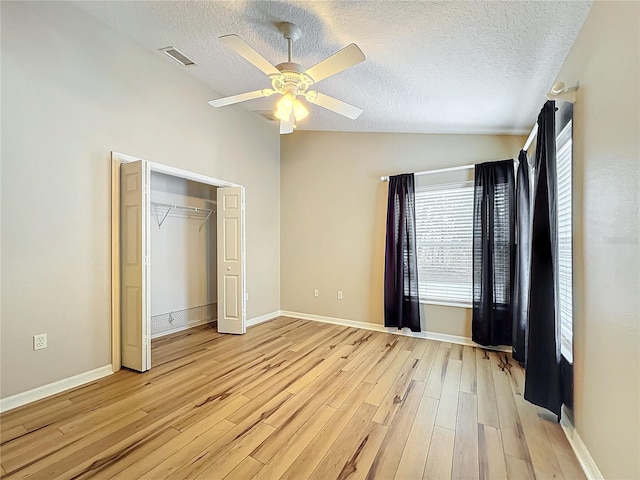 unfurnished bedroom with ceiling fan, lofted ceiling, a textured ceiling, and light wood-type flooring