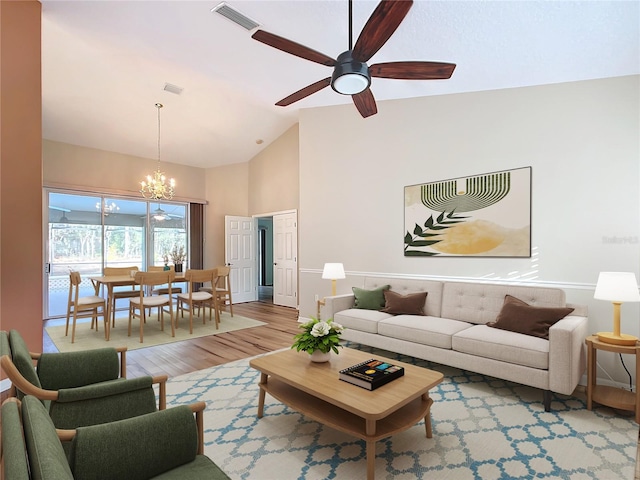 living room featuring wood-type flooring, ceiling fan with notable chandelier, and high vaulted ceiling