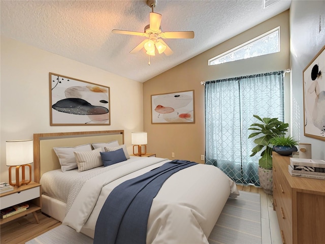 bedroom featuring ceiling fan, lofted ceiling, hardwood / wood-style floors, and a textured ceiling