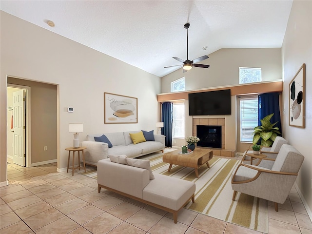 tiled living room with a tiled fireplace, high vaulted ceiling, and ceiling fan