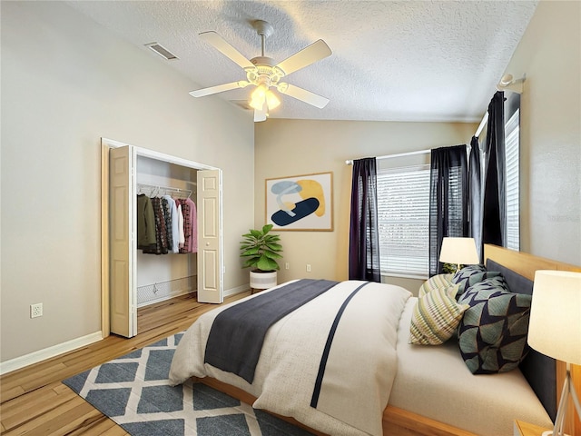 bedroom with lofted ceiling, ceiling fan, light hardwood / wood-style floors, and a textured ceiling