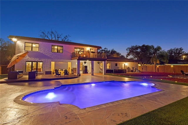 pool at dusk with a patio area