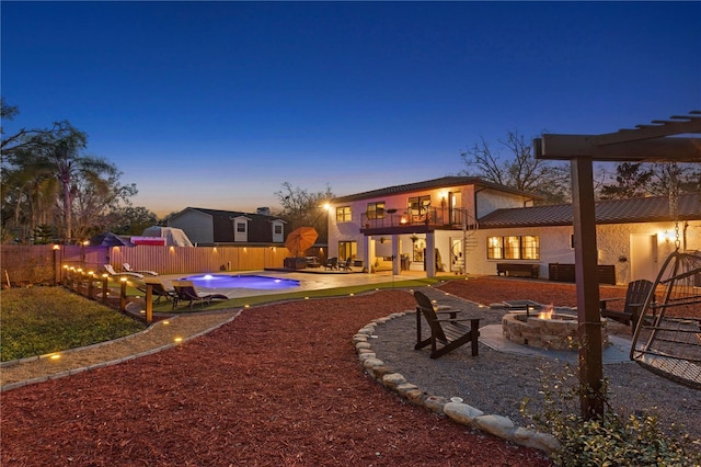 exterior space with a fenced in pool, a balcony, a patio area, and an outdoor fire pit