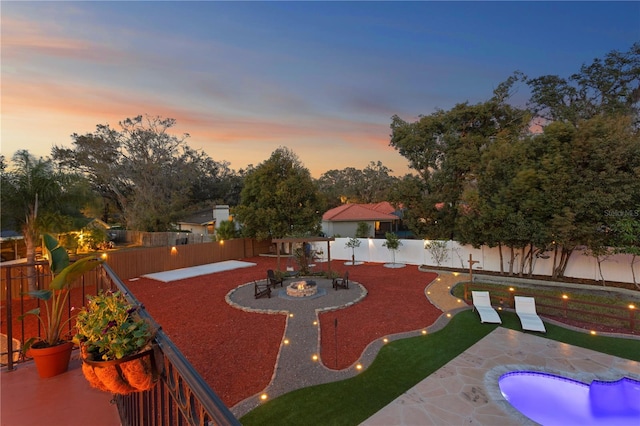 pool at dusk with an outdoor fire pit and a patio