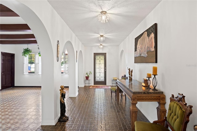 entryway featuring beam ceiling and a chandelier