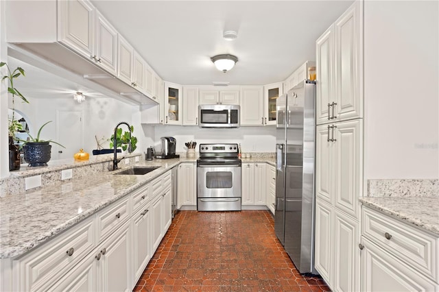 kitchen featuring stainless steel appliances, white cabinetry, sink, and light stone counters