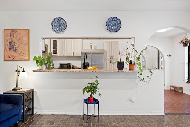 kitchen featuring a breakfast bar area, light stone counters, white cabinetry, stainless steel fridge with ice dispenser, and kitchen peninsula