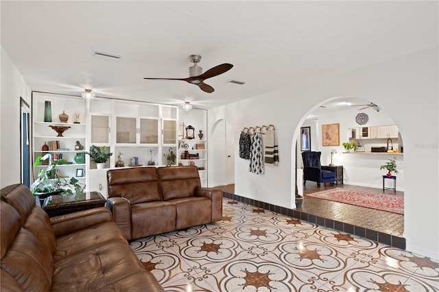 living room featuring light tile patterned floors, built in shelves, and ceiling fan