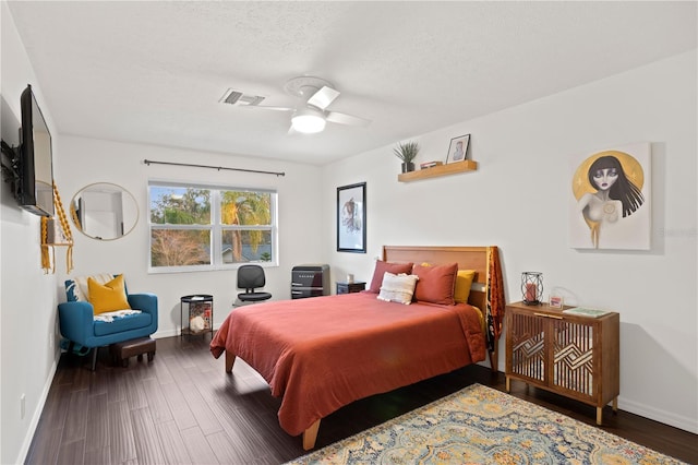 bedroom with dark hardwood / wood-style flooring, ceiling fan, and a textured ceiling