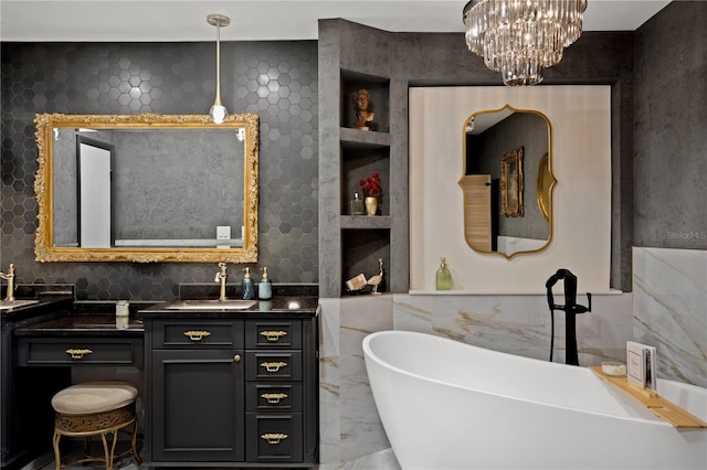 bathroom with an inviting chandelier, vanity, and a tub