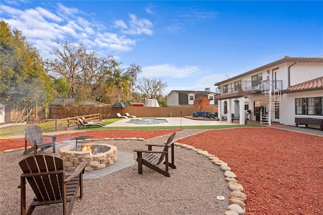 view of yard with a balcony, an outdoor fire pit, a fenced in pool, and a patio