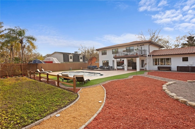 rear view of house featuring a fenced in pool, a patio area, and a balcony