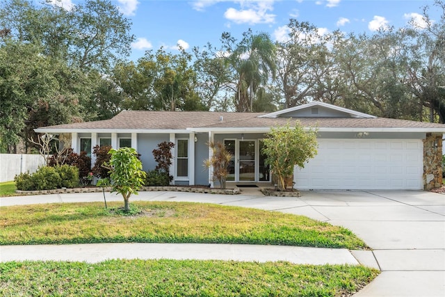 single story home featuring a garage, concrete driveway, a front lawn, and stucco siding