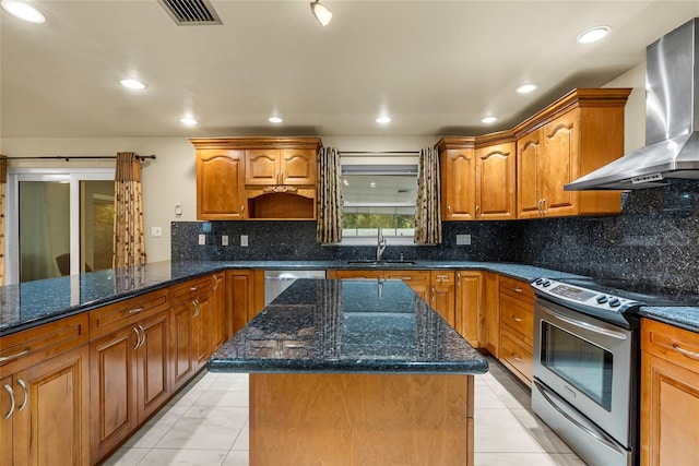 kitchen featuring dark stone countertops, a center island, wall chimney exhaust hood, and appliances with stainless steel finishes